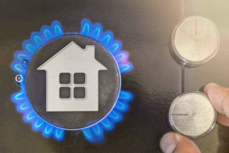 he use of gas as heating at home in winter, the cold season. The concept, the model of the house stands near the flame of a gas boiler.